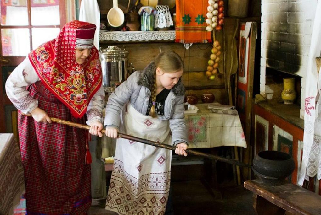 Мама учит дочку вынимать из печи чугунок